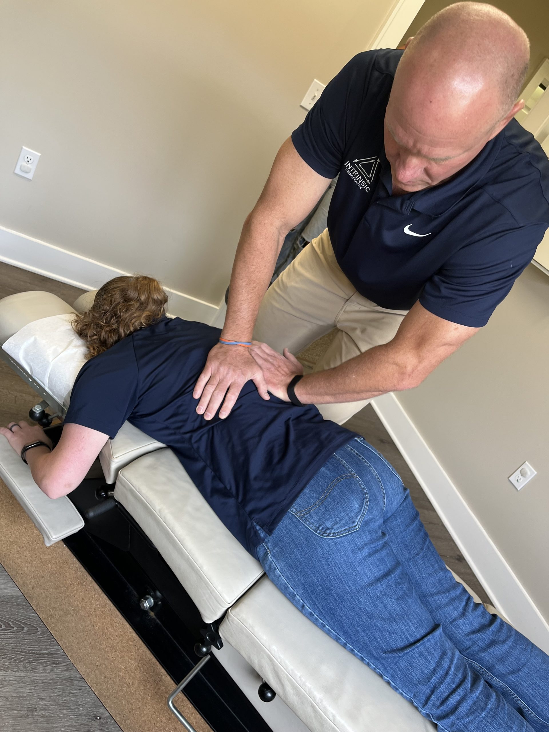 IMG_1067 Chiropractor performing a hands-on spinal adjustment on a patient lying face down on a treatment table