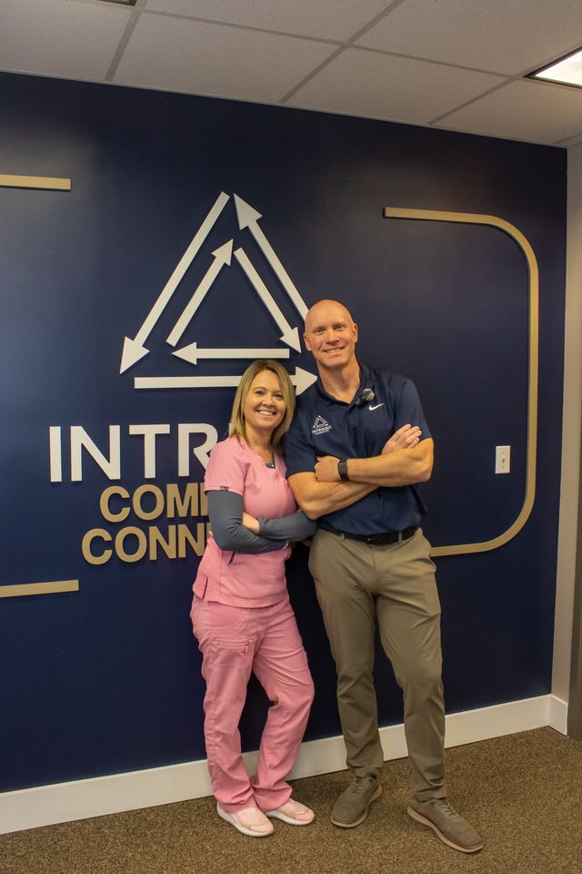 Chiropractic clinic team members standing together in front of Intrinsic Chiropractic office wall